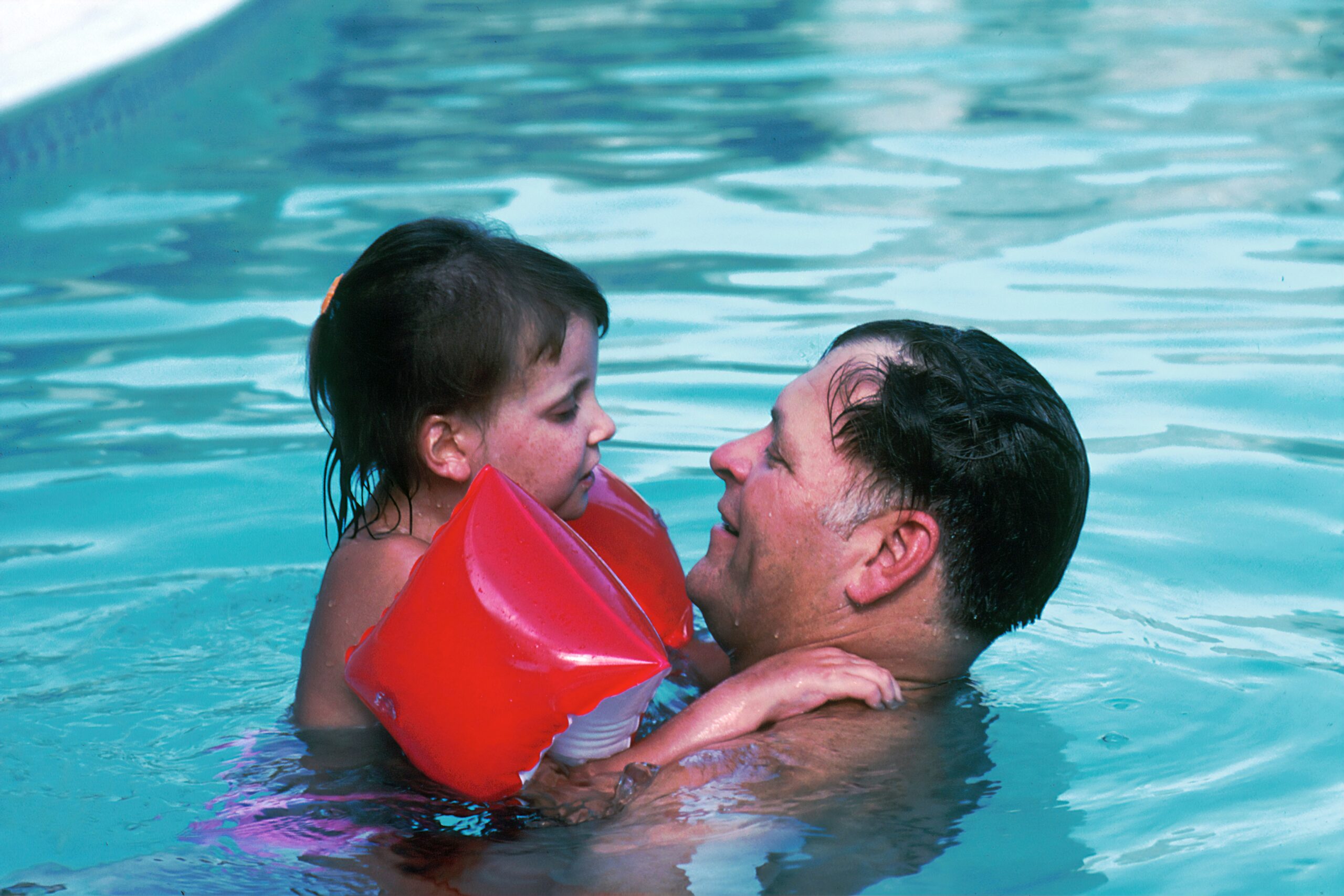 man with toddler girl in swimming pool